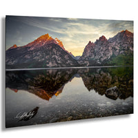 a serene mountain landscape with a calm lake reflecting the vibrant colors of the setting sun.