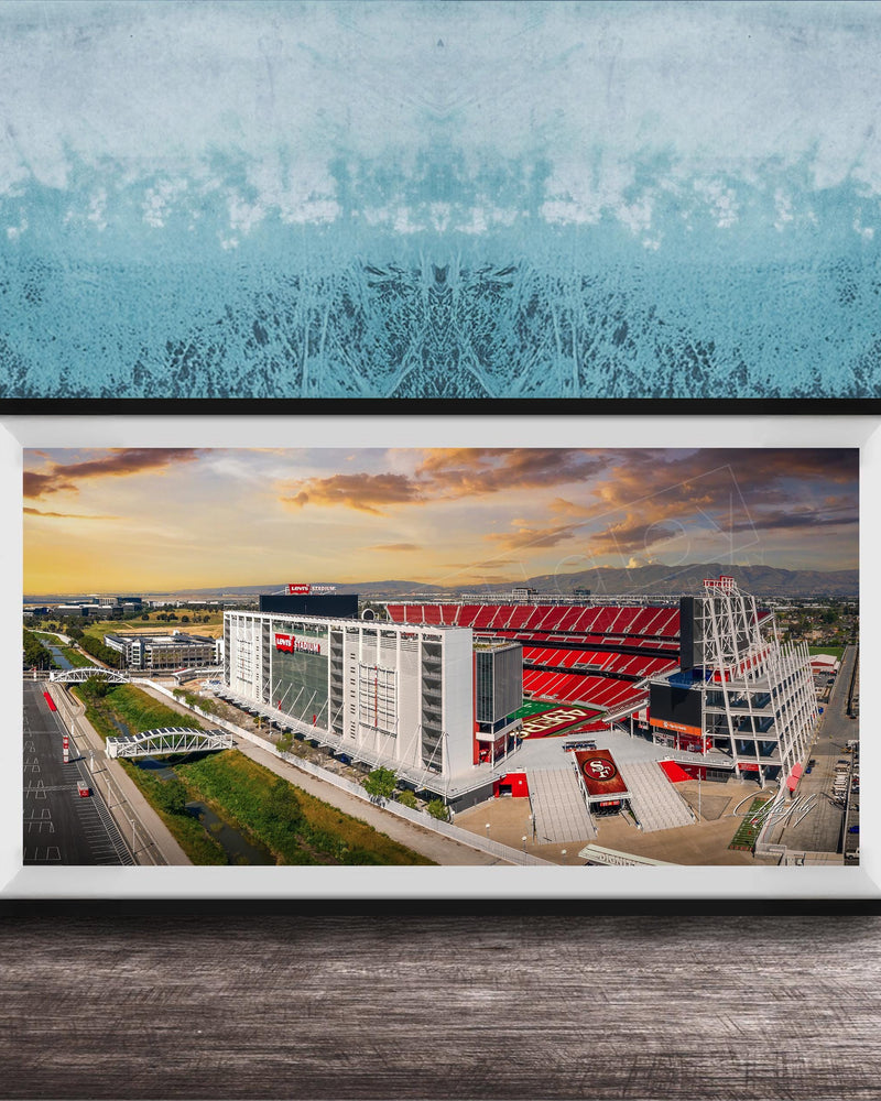 The image is a framed photograph of a large stadium with a red roof, set against a backdrop of a blue sky with clouds.