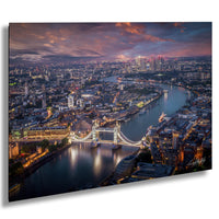 The image is a stunning aerial view of the city of London at night, showcasing the iconic Tower Bridge and the River Thames. The cityscape is illuminated by the glow of the lights, creating a vibrant and captivating scene.
