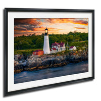 A framed photograph depicting a lighthouse on a rocky coastline, with a colorful sunset sky in the background.