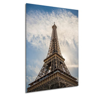 the Eiffel Tower, a famous landmark in Paris, France, standing tall against a blue sky with clouds.