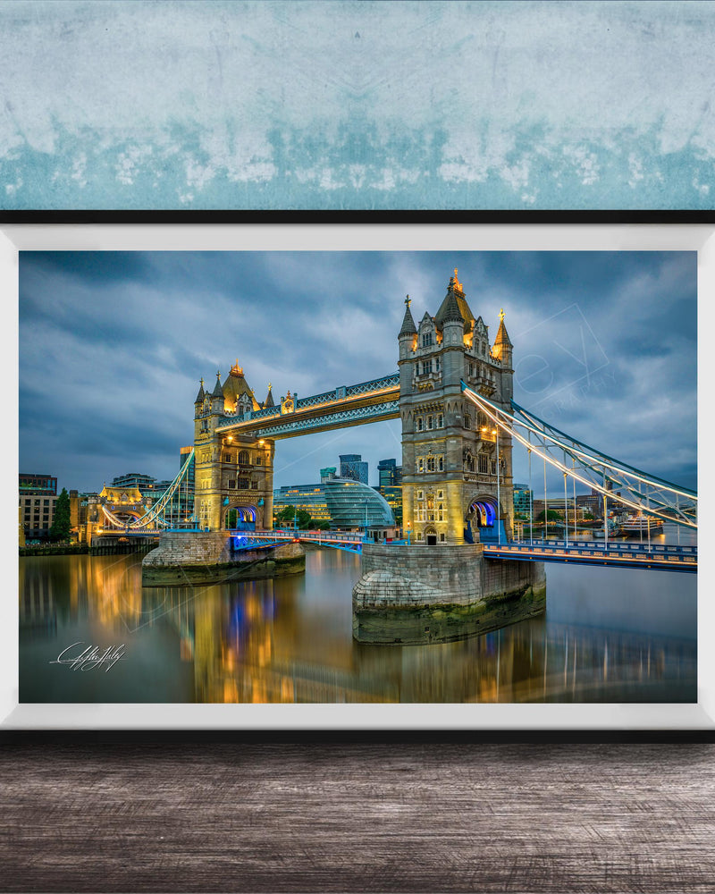 A framed photograph of the iconic Tower Bridge in London, England, illuminated at night against a cloudy sky.