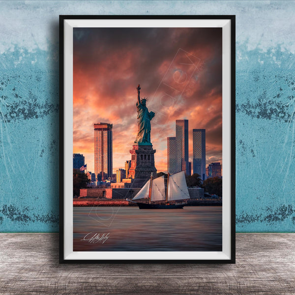 a framed photograph of the Statue of Liberty in New York City, with the city skyline in the background and a sailboat in the foreground.