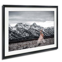 A framed photograph depicting a teepee in a snowy mountain landscape with a cloudy sky.