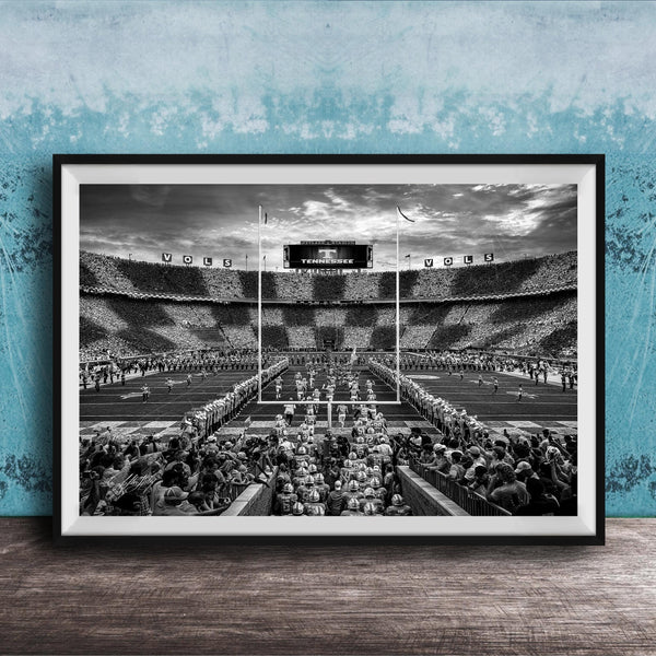 A black and white photograph of a crowded football stadium with a large audience, featuring a scoreboard and field markings.