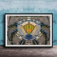 The image is an aerial view of a baseball stadium, featuring a large field surrounded by parking lots and other structures.