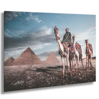 A man rides a camel in front of the iconic pyramids of Giza, Egypt, with a cloudy sky in the background.
