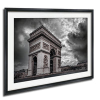 The image is a black and white photograph of the Arc de Triomphe in Paris, France, with dramatic clouds in the background.