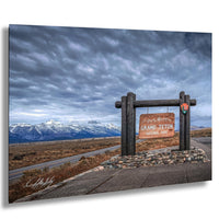 a scenic view of the Grand Teton National Park, with snow-capped mountains in the background and a cloudy sky above.