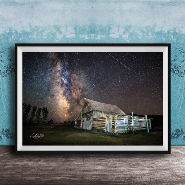 A framed photograph depicting a rustic wooden barn under a starry night sky, with the Milky Way galaxy visible in the background.