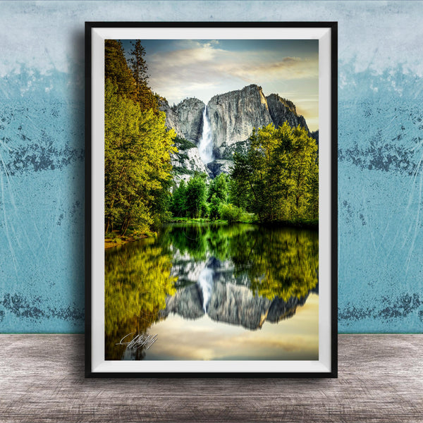 A framed photograph of a serene landscape with a waterfall cascading down a rocky cliff, surrounded by lush green trees and reflected in a calm lake below.