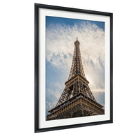 the Eiffel Tower, a famous landmark in Paris, France. The tower is captured from a low angle, emphasizing its height and grandeur against a cloudy sky.