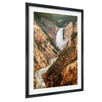 A framed photograph depicting a scenic view of a waterfall cascading down a steep, rocky cliff surrounded by lush green trees.