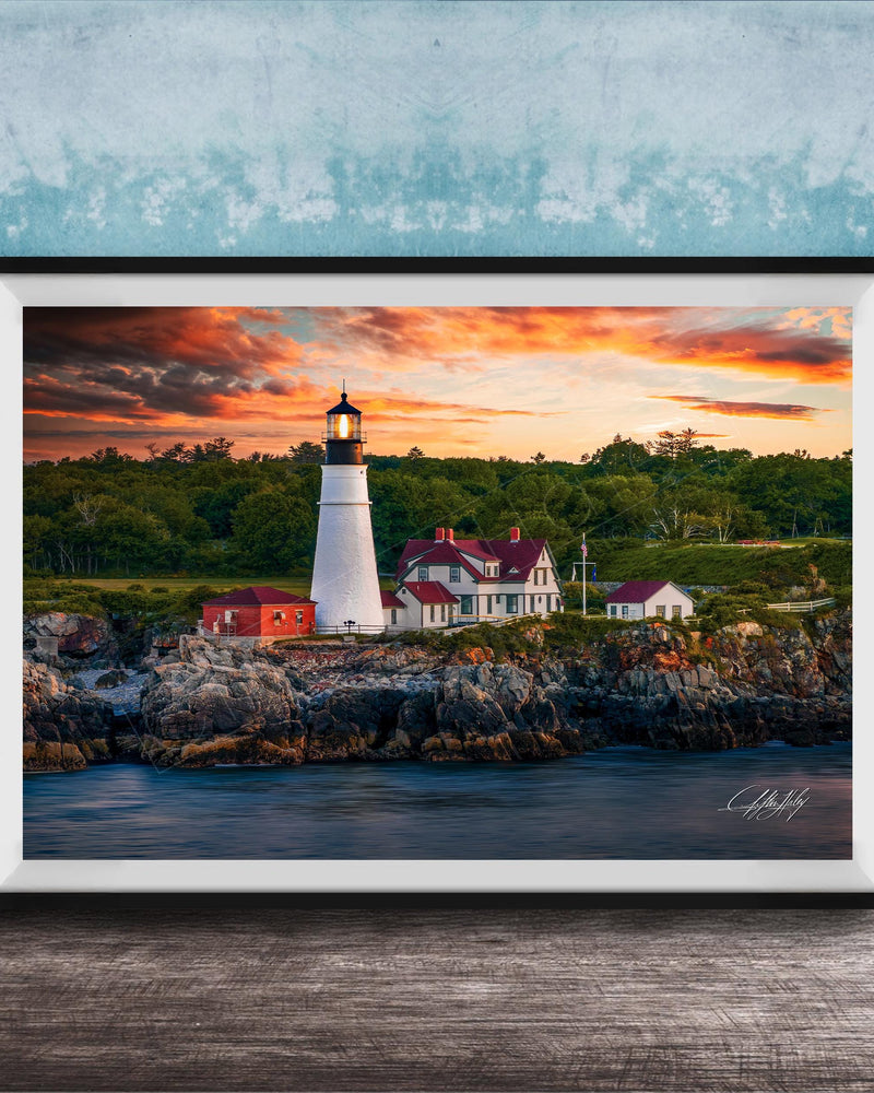 A framed photograph of a lighthouse on a rocky shore, with a colorful sunset sky in the background.