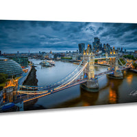 a cityscape with a large suspension bridge spanning a river, surrounded by tall buildings and a cloudy sky.