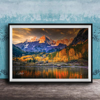 The image is a framed photograph depicting a scenic mountain landscape with a lake in the foreground, surrounded by trees with autumn foliage.