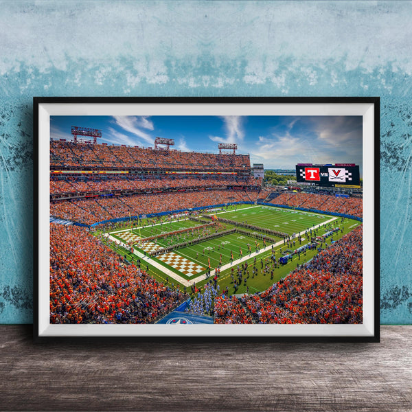 A framed photograph of a crowded football stadium during a game, with the field and stands filled with spectators.