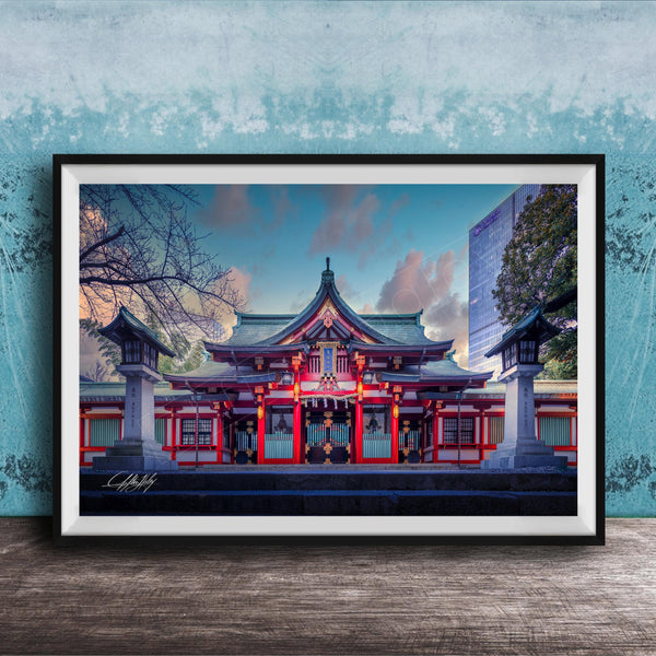 A framed photograph of a traditional Japanese temple with a red roof and white walls, set against a blue sky with clouds.