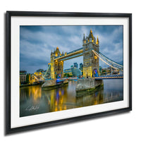 A framed photograph of the iconic Tower Bridge in London, England, illuminated at night against a cloudy sky.
