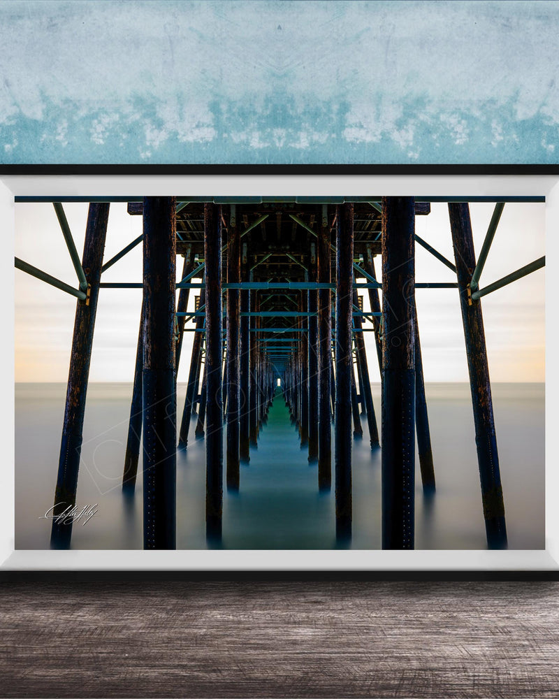 The image is a framed photograph of a long pier with multiple wooden columns extending into the distance, creating a sense of depth and perspective.