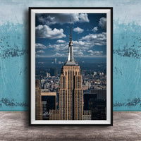 A framed photograph of the iconic Empire State Building in New York City, with the cityscape of Manhattan visible in the background.
