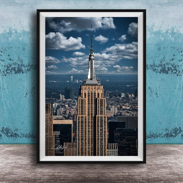 A framed photograph of the iconic Empire State Building in New York City, with the cityscape of Manhattan visible in the background.