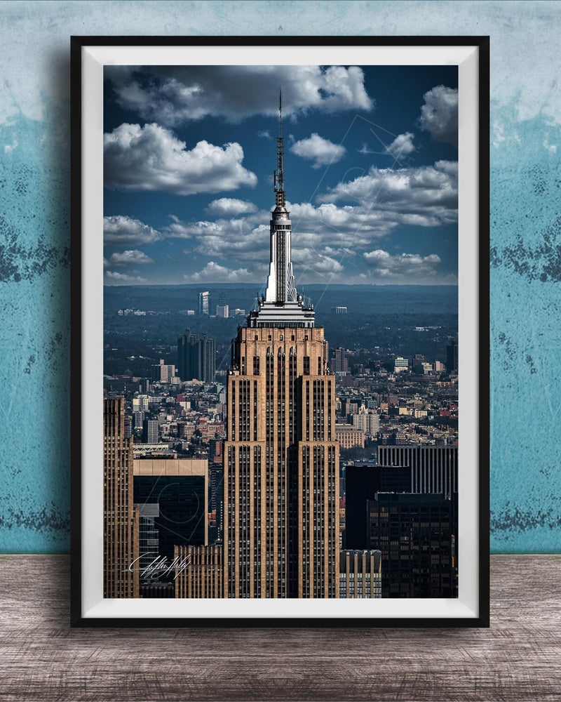 A framed photograph of the iconic Empire State Building in New York City, with the cityscape of Manhattan visible in the background.