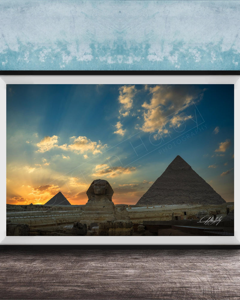 the Great Pyramids of Giza against a stunning sunset sky, with the Sphinx in the foreground.