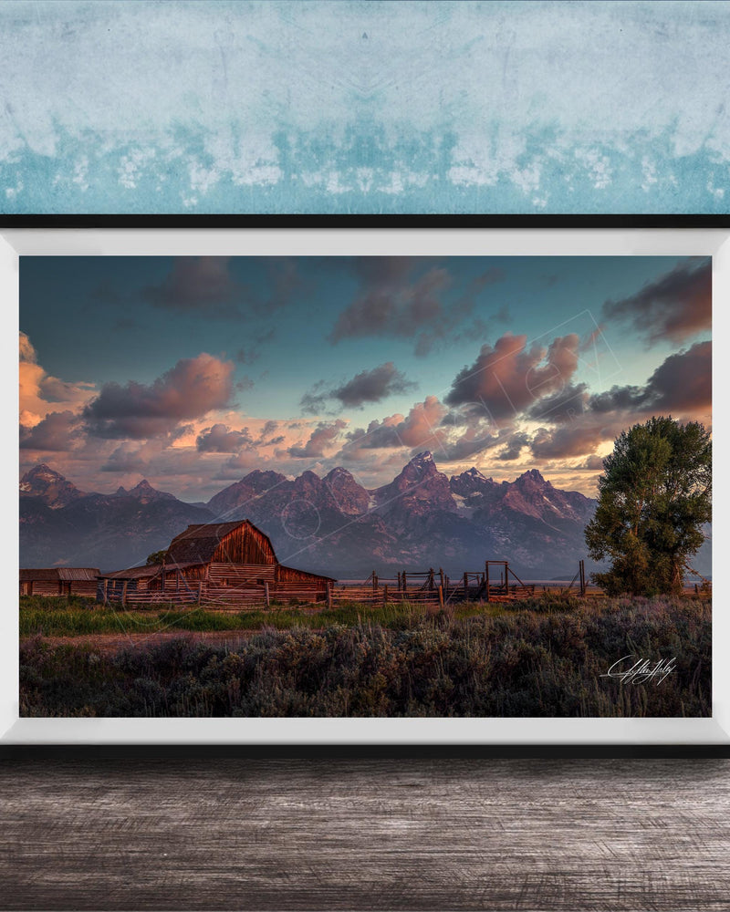 a rustic wooden barn nestled in a grassy field, with majestic mountains in the background under a vibrant sky.
