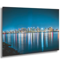 A stunning nighttime cityscape with a skyline of illuminated buildings reflected in the calm waters of a large body of water, creating a mesmerizing and vibrant scene.