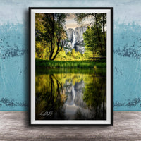 A framed photograph of a serene landscape with a waterfall reflected in a calm lake, surrounded by lush greenery and trees.