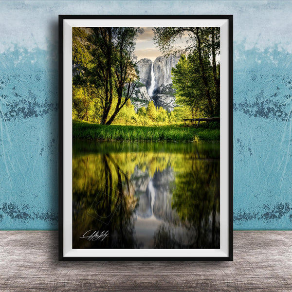 A framed photograph of a serene landscape with a waterfall reflected in a calm lake, surrounded by lush greenery and trees.