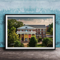 A framed photograph of the Peabody Hall building, a historic brick structure with a prominent pediment and columns, surrounded by trees and a blue sky.