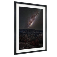 a breathtaking view of a starry night sky over a rugged, mountainous landscape.