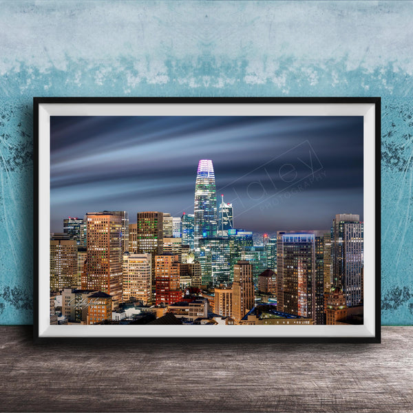 A framed photograph of a city skyline at night, with numerous illuminated skyscrapers and buildings against a dark sky.