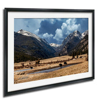 a serene landscape with a river flowing through a valley, surrounded by snow-capped mountains under a blue sky with clouds.