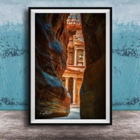 A framed photograph of a narrow passage between two large rock formations, with a building visible through the opening.