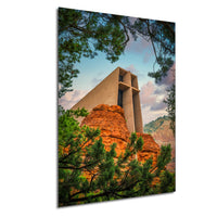 a large, modern building with a distinctive architectural design, situated in a mountainous landscape with red rock formations and lush green trees framing the structure.