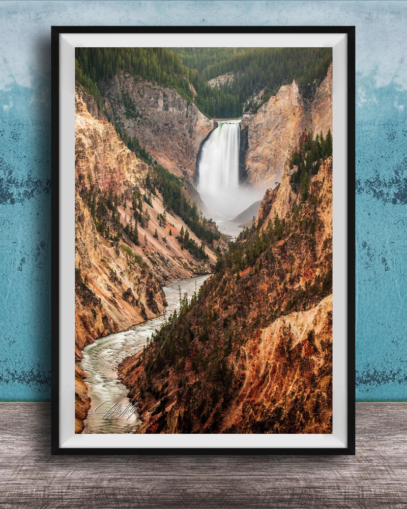 A framed photograph of a majestic waterfall cascading down a rugged, mountainous landscape.