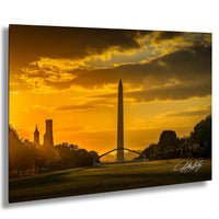 a serene sunset over a park, with the Washington Monument and other buildings silhouetted against the vibrant orange sky.