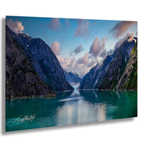 a serene landscape with a large body of water surrounded by towering mountains, with a clear blue sky and fluffy white clouds above.
