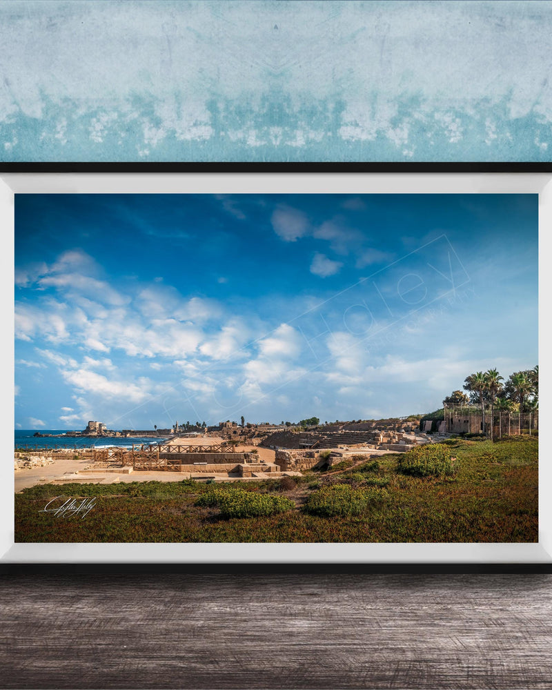 The image is a framed photograph of a beach with palm trees and a castle in the distance, set against a blue sky with white clouds.