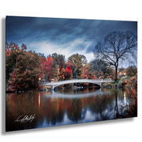 a serene autumn landscape with a white bridge spanning a calm lake, surrounded by trees with vibrant red and orange foliage.