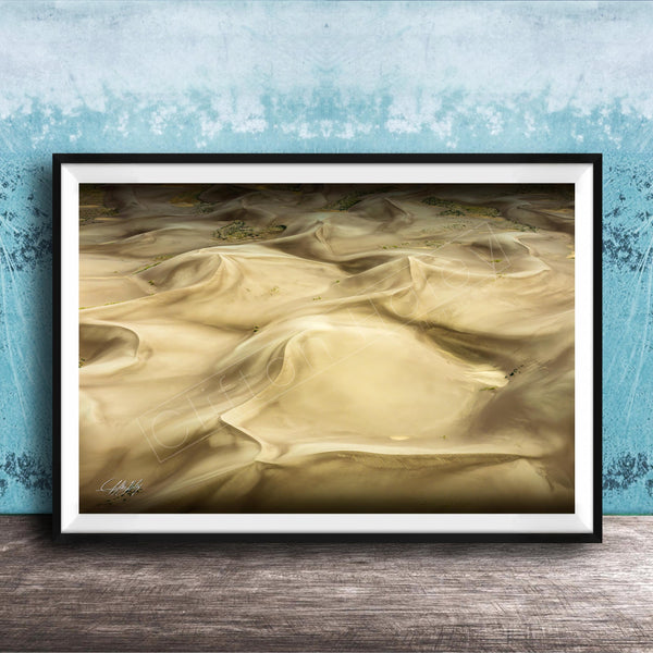 The image is a framed photograph of sand dunes, with a blue wall in the background.