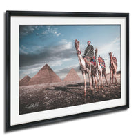 A man riding a camel in front of the iconic pyramids of Giza, Egypt.
