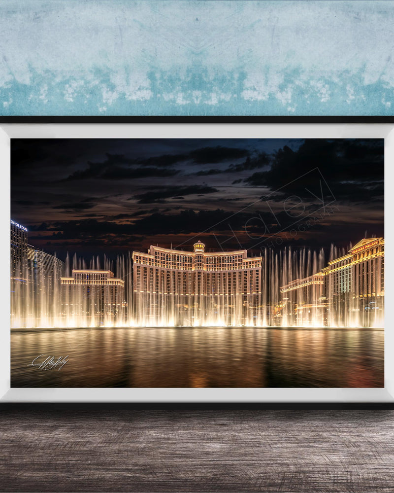 A framed photograph of the Bellagio Fountains in Las Vegas at night, with the fountains illuminated and creating a stunning reflection on the water surface.