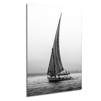 This luxury black and white fine art photograph captures a felucca sail boat drifting along the Nile River at sunset near Luxor, Egypt. Soft fog and minimalist composition create a timeless, monochrome aesthetic rooted in Egyptian river culture. Ideal for collectors and interior designers seeking refined, museum-quality wall art that embodies elegance, simplicity, and enduring calm.