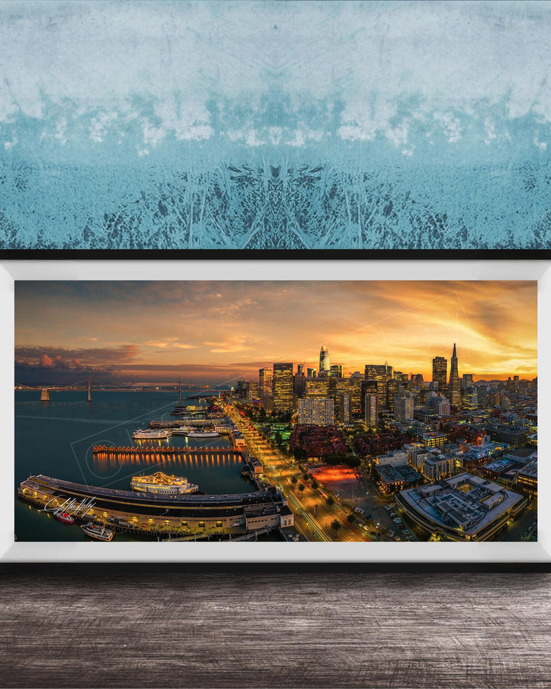 The image is a framed photograph of a cityscape at sunset, featuring a skyline with tall buildings and a harbor with boats.