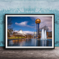 A framed photograph of the iconic Space Needle in Nashville, Tennessee, with a fountain in the foreground and a blue sky with clouds in the background.
