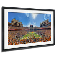 A framed photograph of a crowded football stadium with a large field, multiple levels of seating, and a large scoreboard in the center.